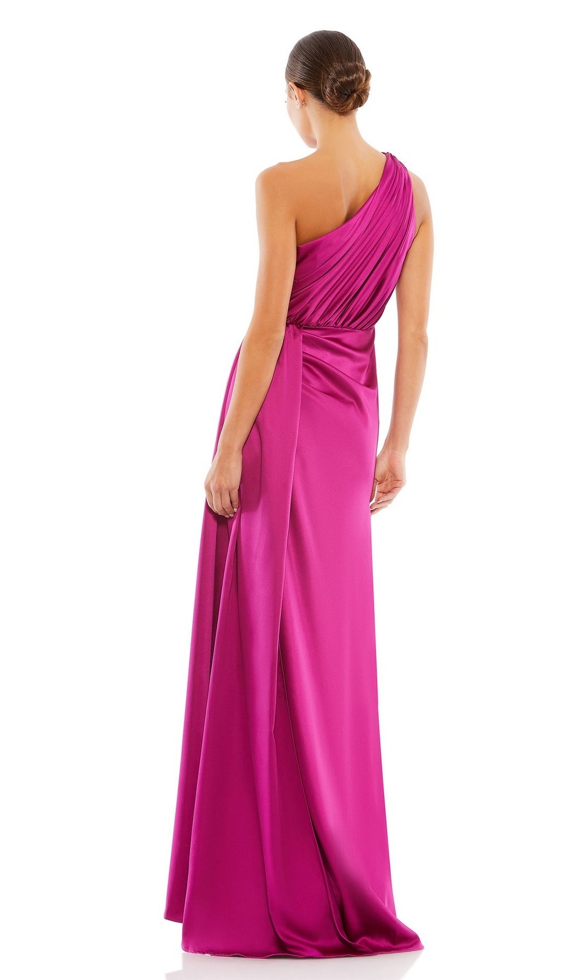 A woman with her hair in a low bun stands facing away against a white background, wearing the bright pink Mac Duggal 26654 One-Shoulder Long Formal Dress, a floor-length Grecian evening gown.